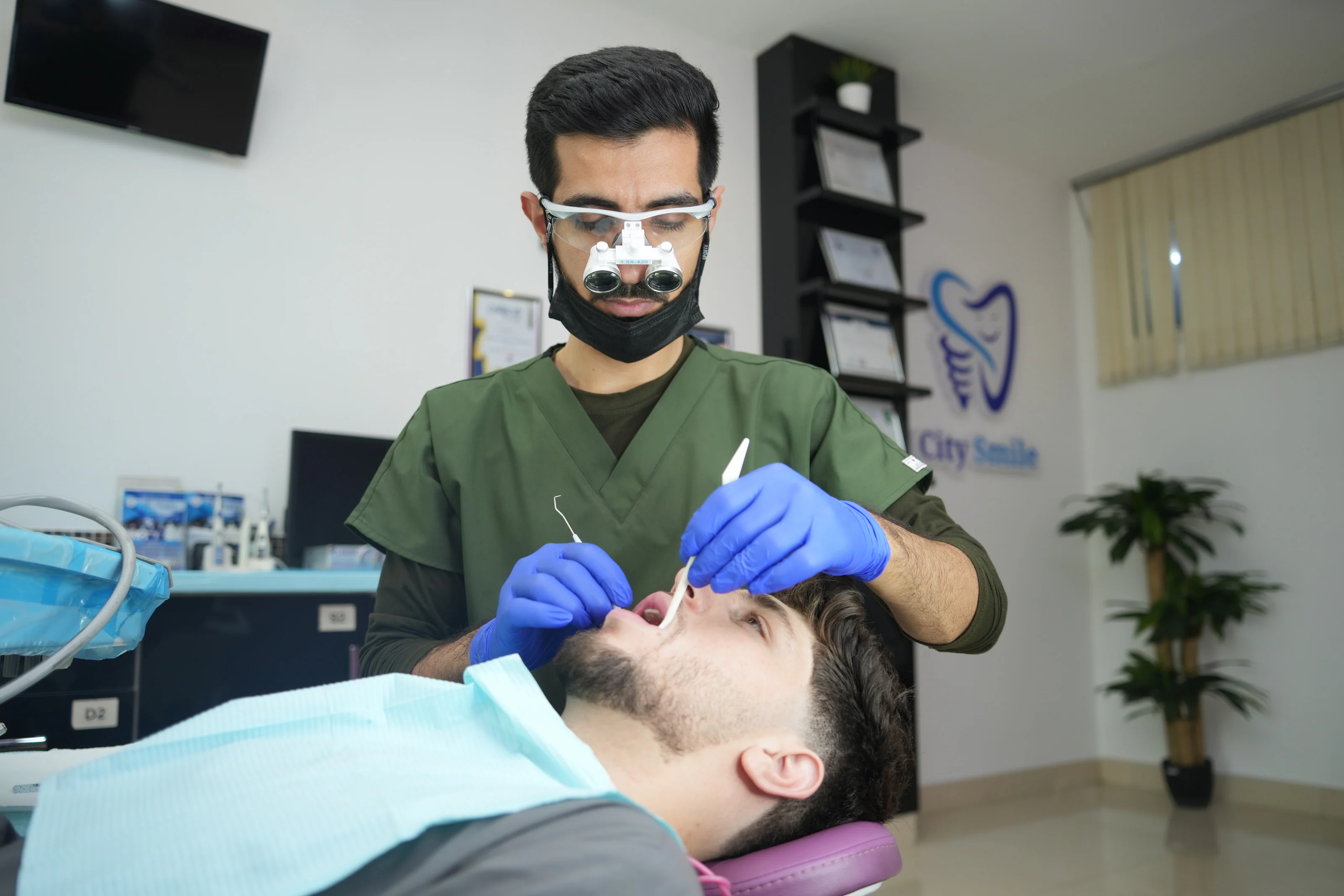 Dr. Arash Kiumars examining a patient with dental loupes
