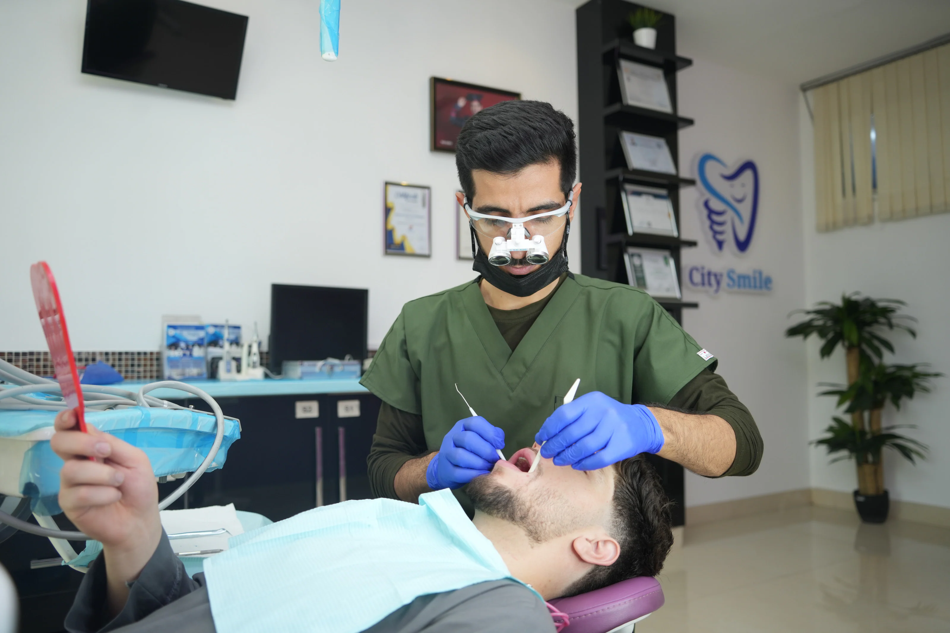 Dr. Arash Kiumars examining a patient who holds a hand mirror