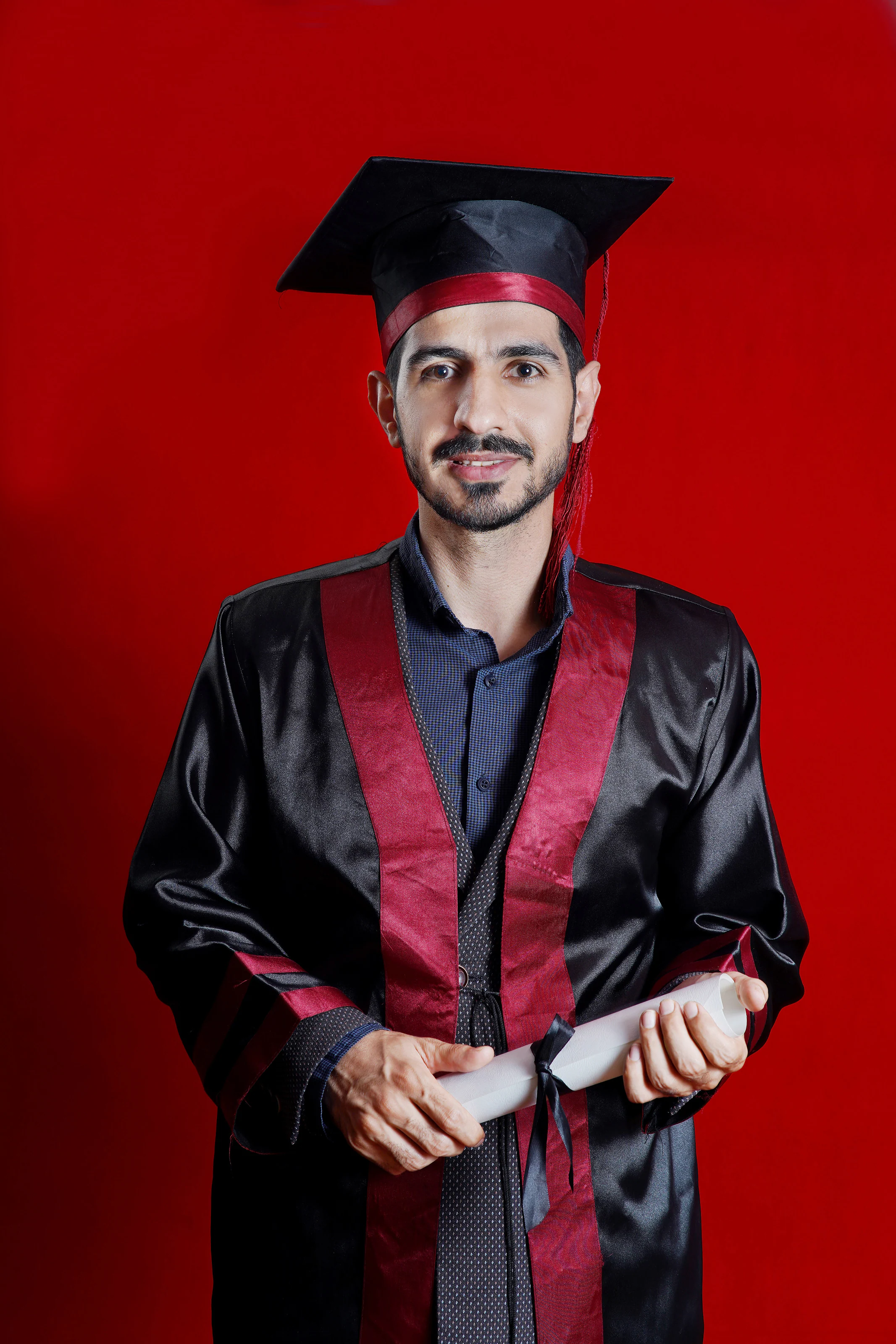 Graduation portrait of Dr. Arash Kiumars holding his diploma scroll